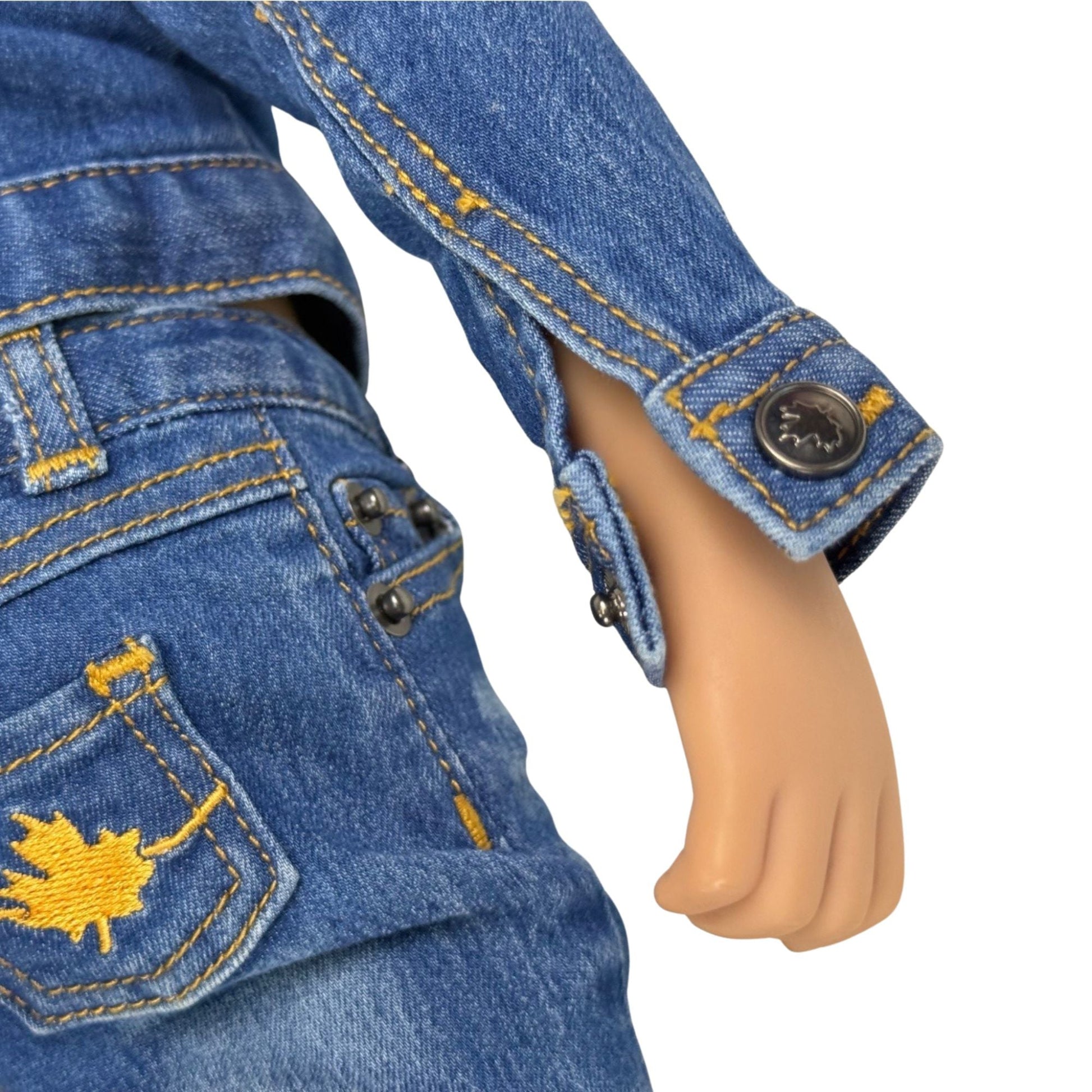 Close-up of a doll wearing blue jeans with a maple leaf design.