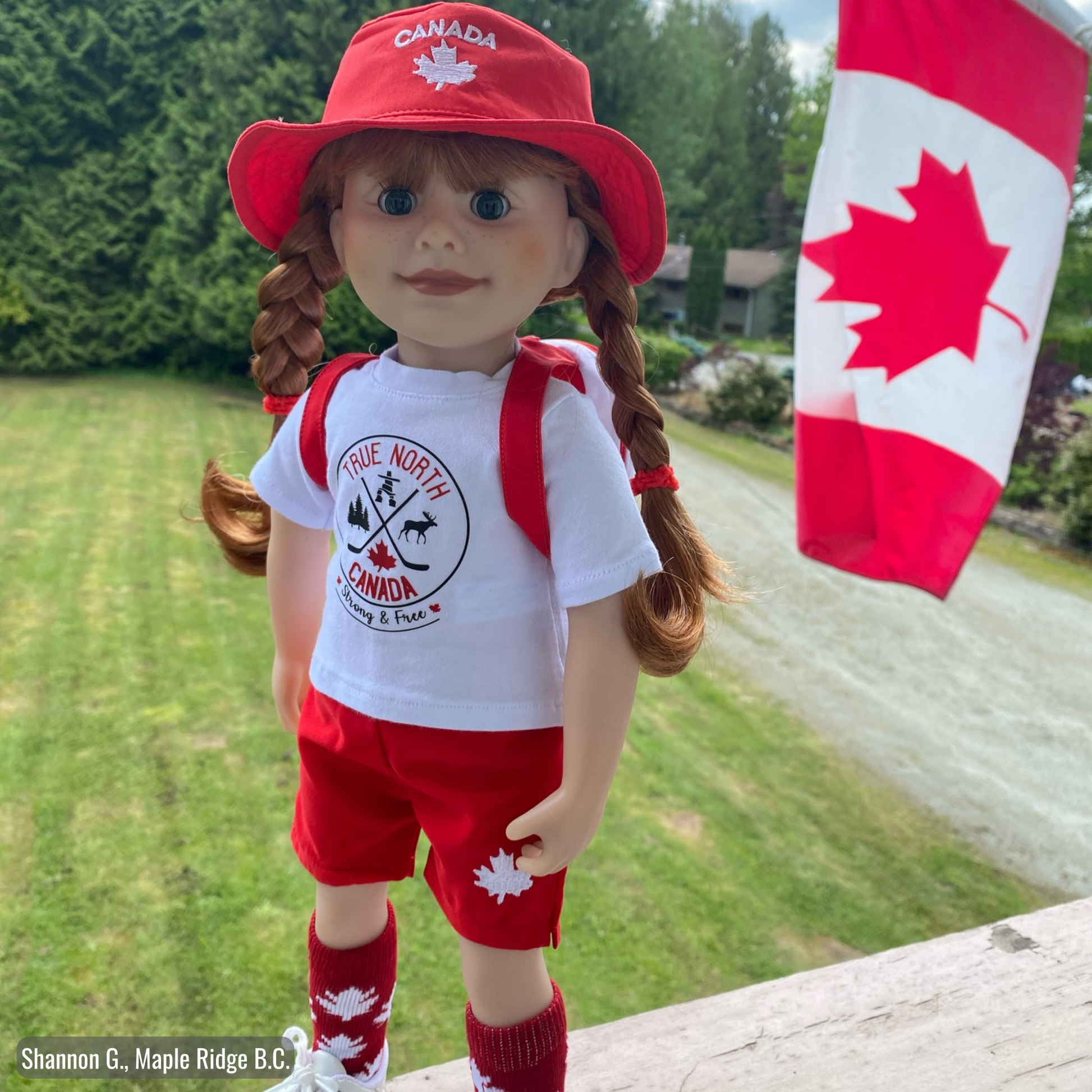 18-inch doll wearing canadian themed red shorts, bucket hat, shirt with true north strong and free emblem, and backpack with embroidered mapleleaf.