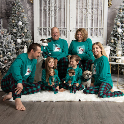 family all wearing the matching family pjs at Christmas with matching doll and dog