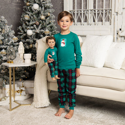 boy wearing pajamas that match the doll's pajamas for the holidays