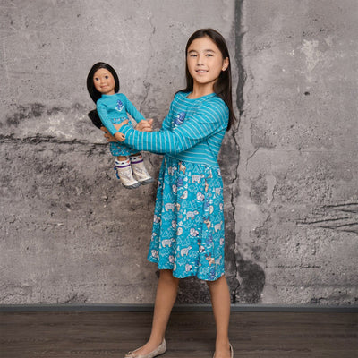 Girl and doll wearing dress-alike dresses with a northern animals motif.