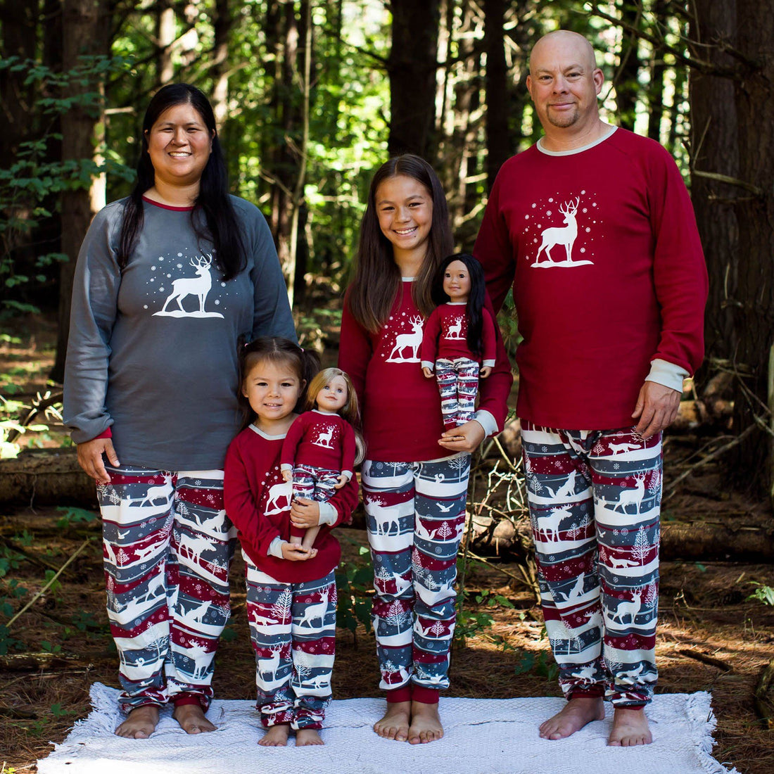 Mom dad two children and 18 inch dolls wearing matching pajamas with a winter theme.