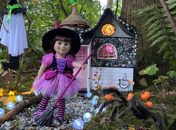 a friendly witch doll in a beautiful pink costume in front of her house in the forest
