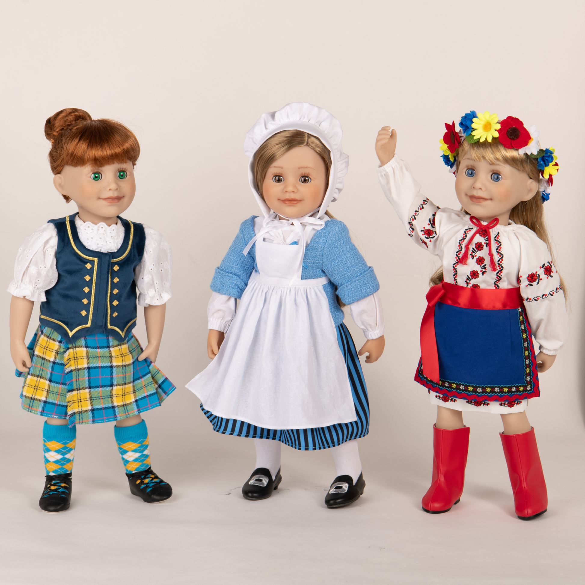 three 18-inch dolls wearing pioneer Quebecois, Ukrainian dance and highland dance outfits