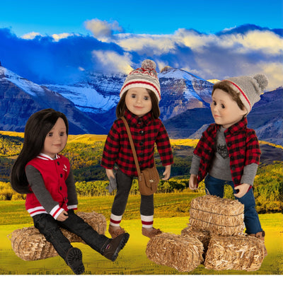 Boy and girl Maplelea dolls sitting in a field with Canadiana style outfits including varsity jacket