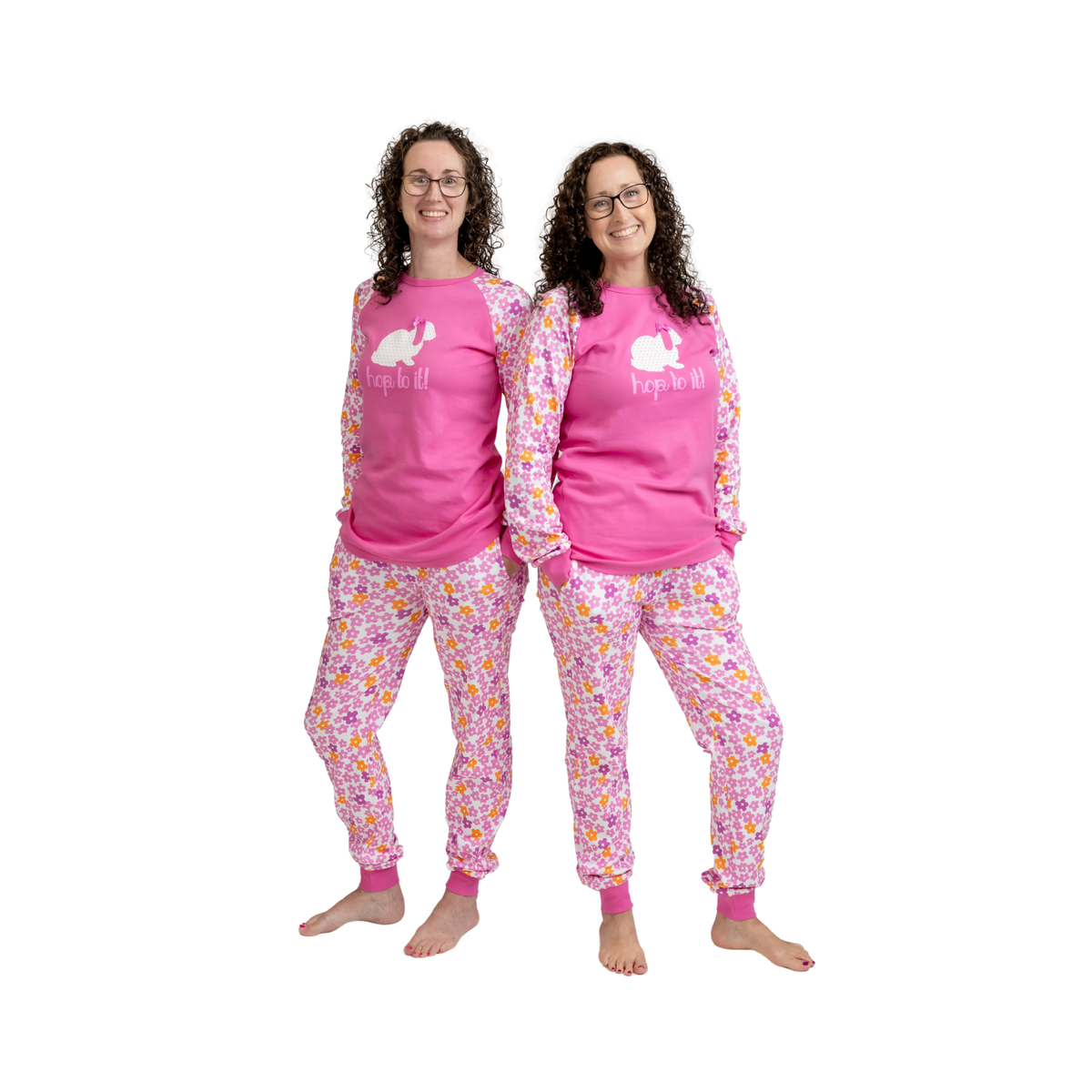 Two women modeling matching pink long-sleeve pajama tops and floral pajama pants against a plain white background.