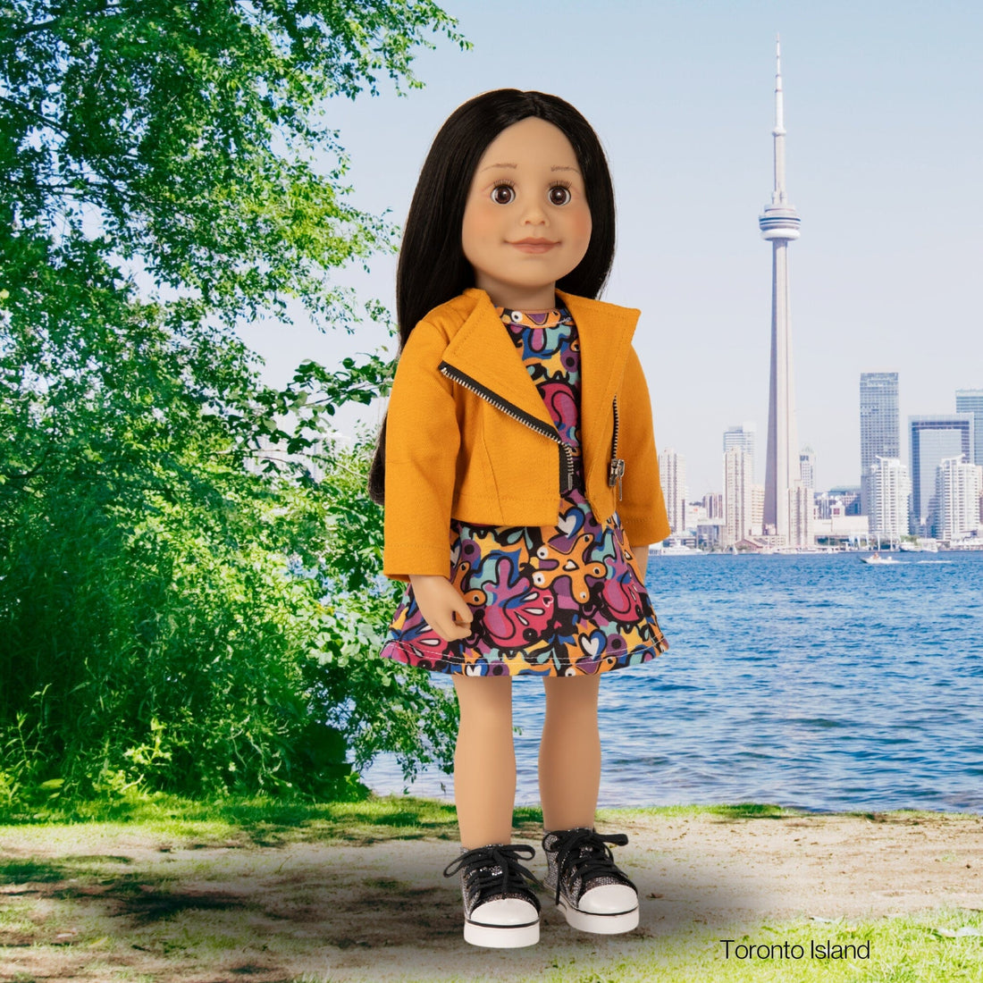 Maplelea doll Alexi from Toronto wearing orange moto jacket, printed graffiti dress and metallic runners