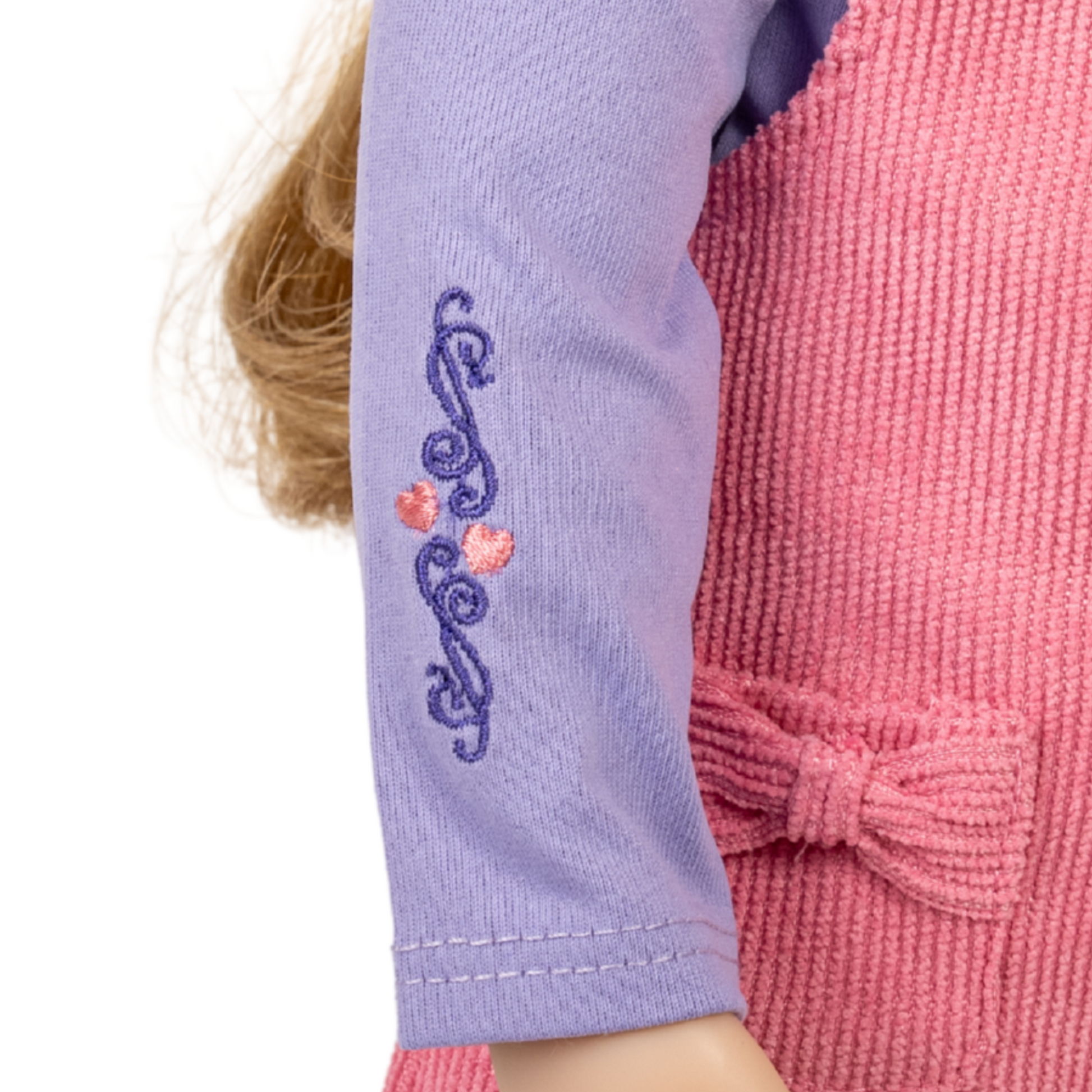 Close-up of a 18-inch doll wearing a purple sleeve with decorative embroidery.
