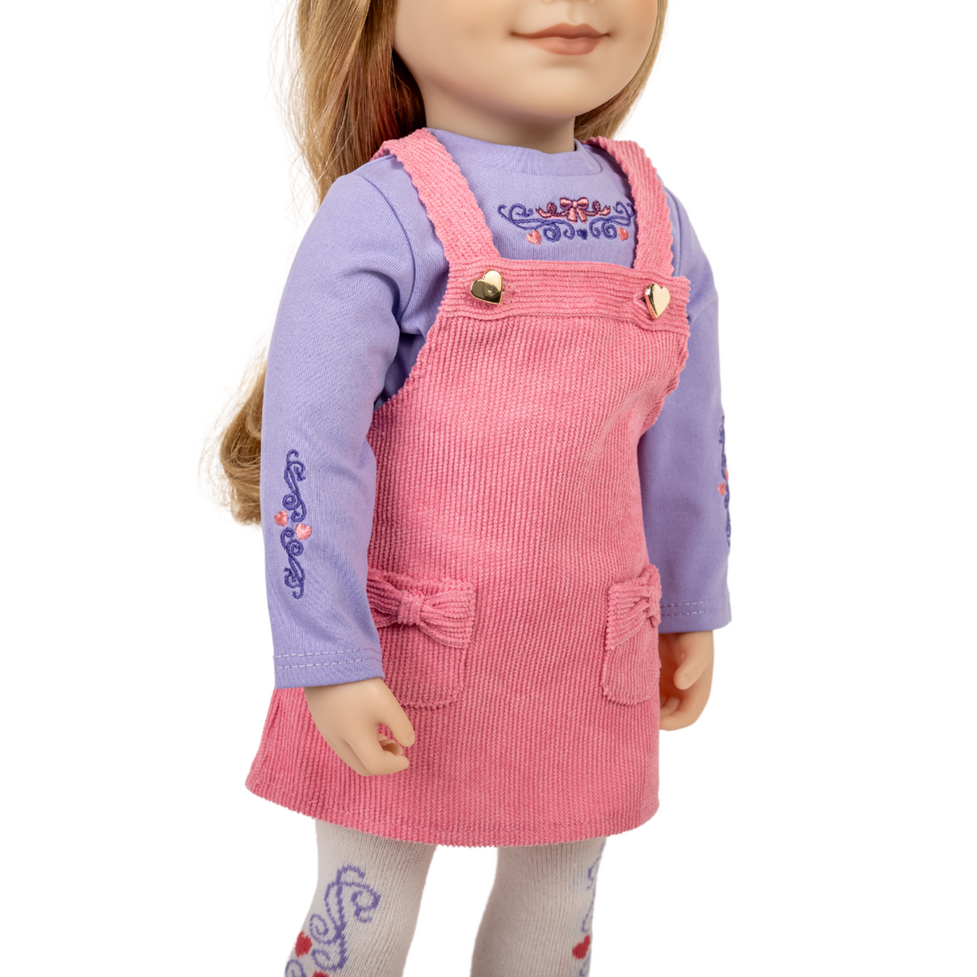 18-inch doll wearing a pink corduroy dress over a purple shirt.