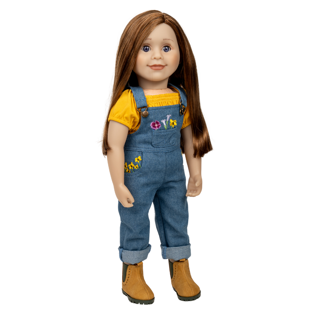 18-inch doll wearing a yellow shirt and blue jean overalls with floral embroidery. Flowers of Salt spring island.