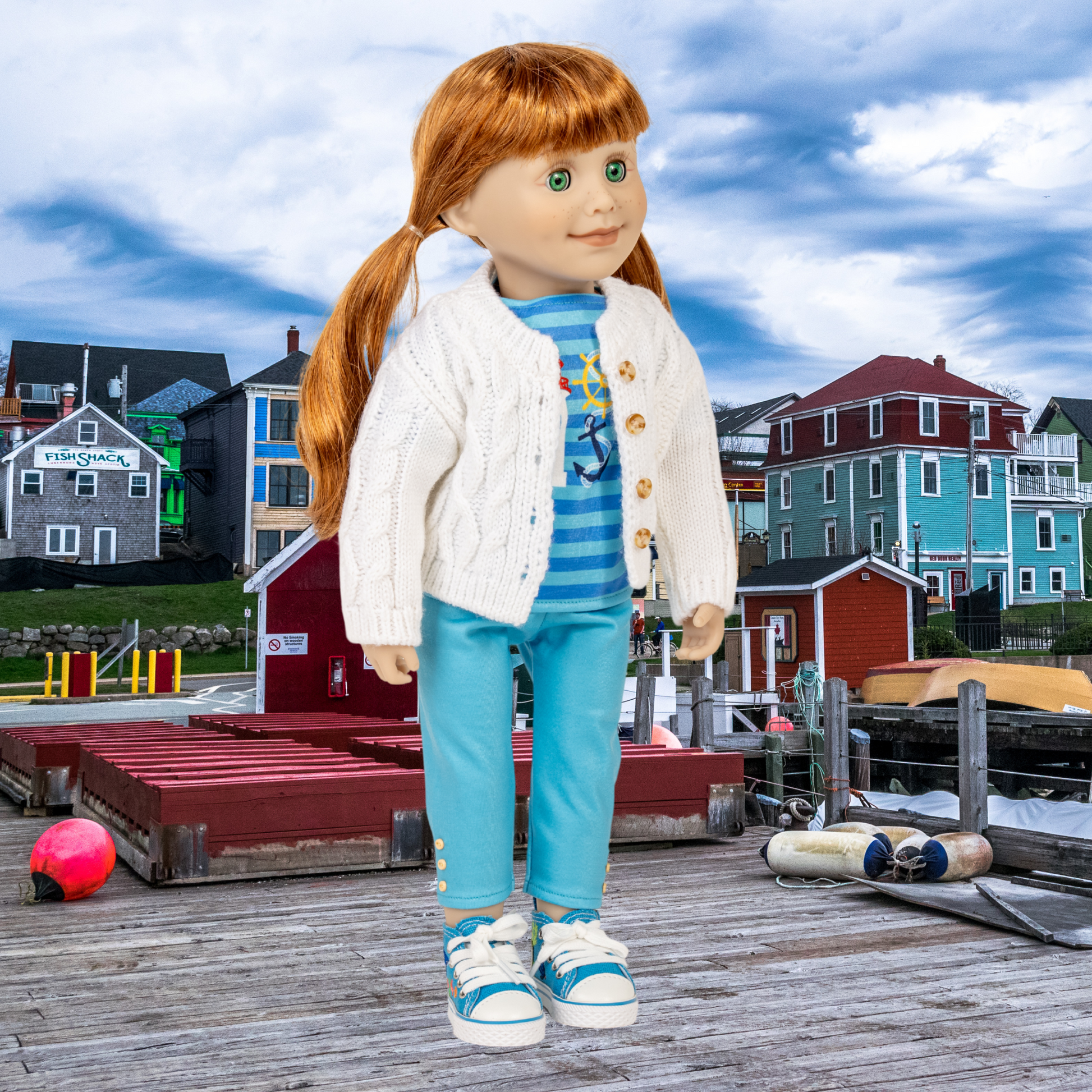 18-inch doll wearing blue boating outfit standing on a dock in Lunenburg with colourful houses in the background.
