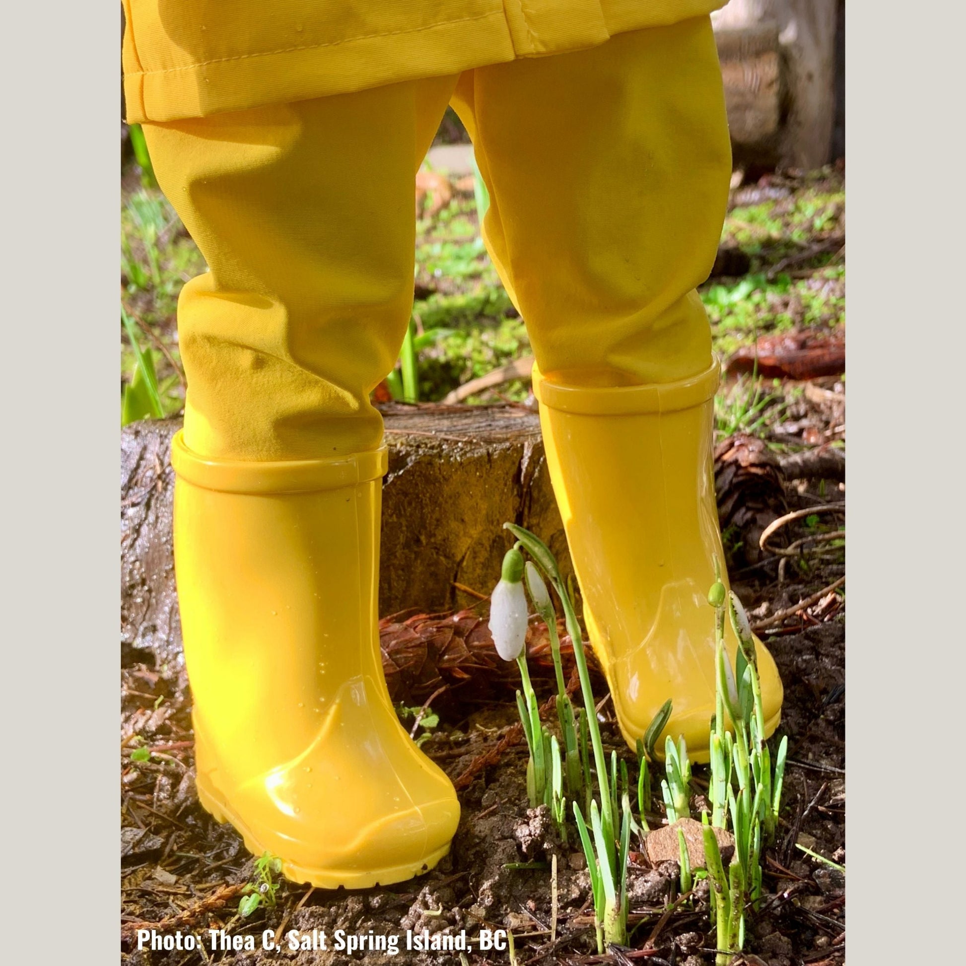 doll wearing yellow rain boots and rain gear with a spring flower.
