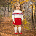 18-inch doll wearing cream coloured turtleneck top with red shirt knee high socks and red shoes.