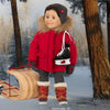 boy doll wearing red parka with hockey skates over his shoulder, pulling a wooden togoggan