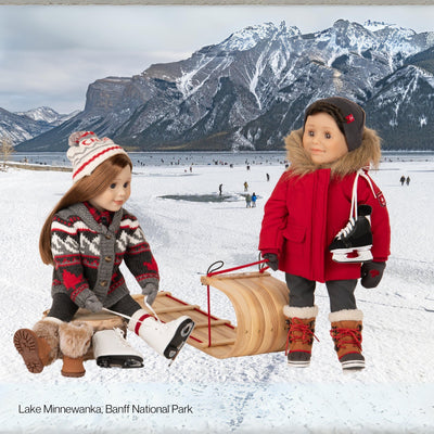 Maplelea girl doll in Canadiana sweater putting on figure skates, boy doll in red parka with skates
