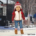 18-inch doll wearing Canada hat and maple leaf mittens with matching socks on a snowy street in Banff.