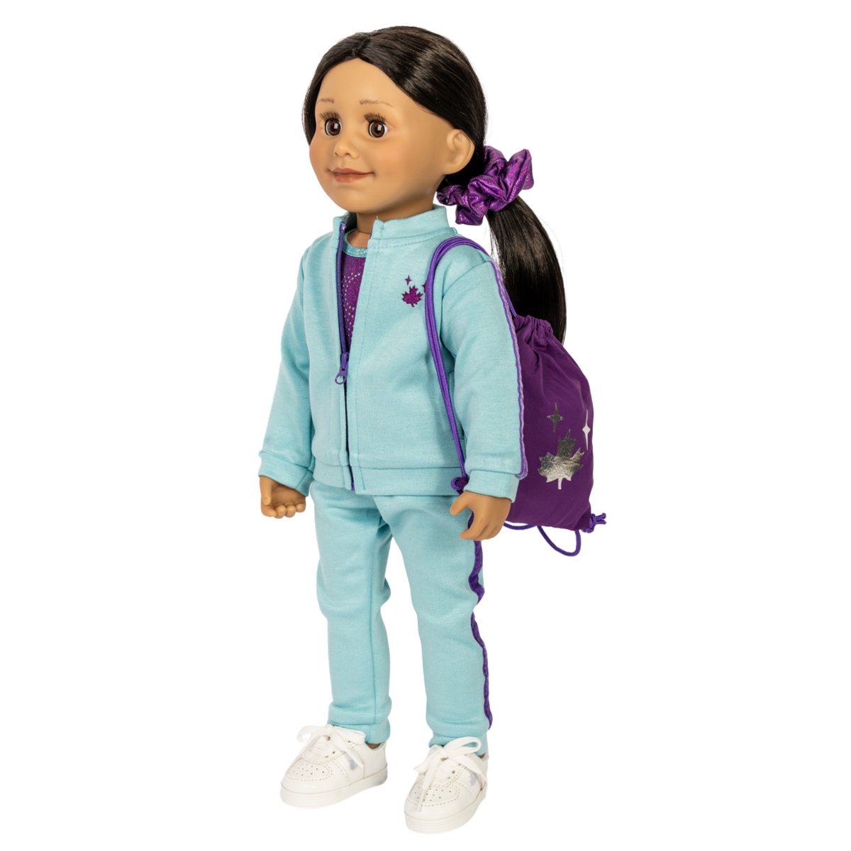 A doll with dark hair in a ponytail wearing a light blue tracksuit with purple side stripes, a purple scrunchie, and a purple drawstring backpack, shown against a plain white background.