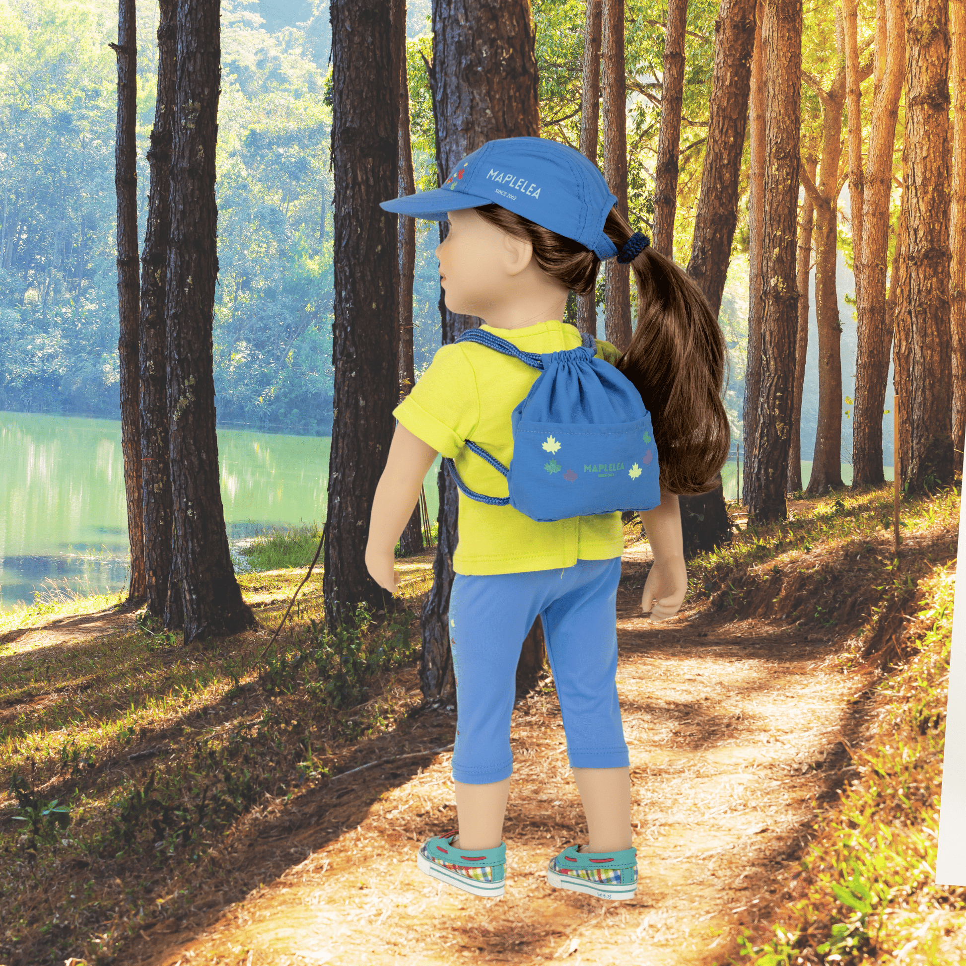 18" doll wearing rolled sleeve t-shirt capris and hat with drawstring backpack on back in the woods 