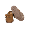 A pair of tan leather baby sandals, one shown from the side and the other from the sole, featuring embossed maple leaf patterns on the bottom. White knee-high doll socks and brown Mary Jane doll shoes included in Edelweiss Dirndl Set
