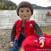 18" boy doll sitting by a lake wearing a Maplelea varsity jacket in real Canadian style