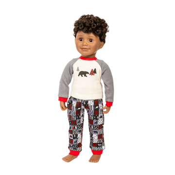 A doll with curly brown hair wearing a two-piece pajama set. The set includes a long-sleeve raglan shirt with a white chest, gray sleeves, red trim, and a bear graphic, paired with matching patterned pants featuring red, black, and gray designs, all on a solid white background.