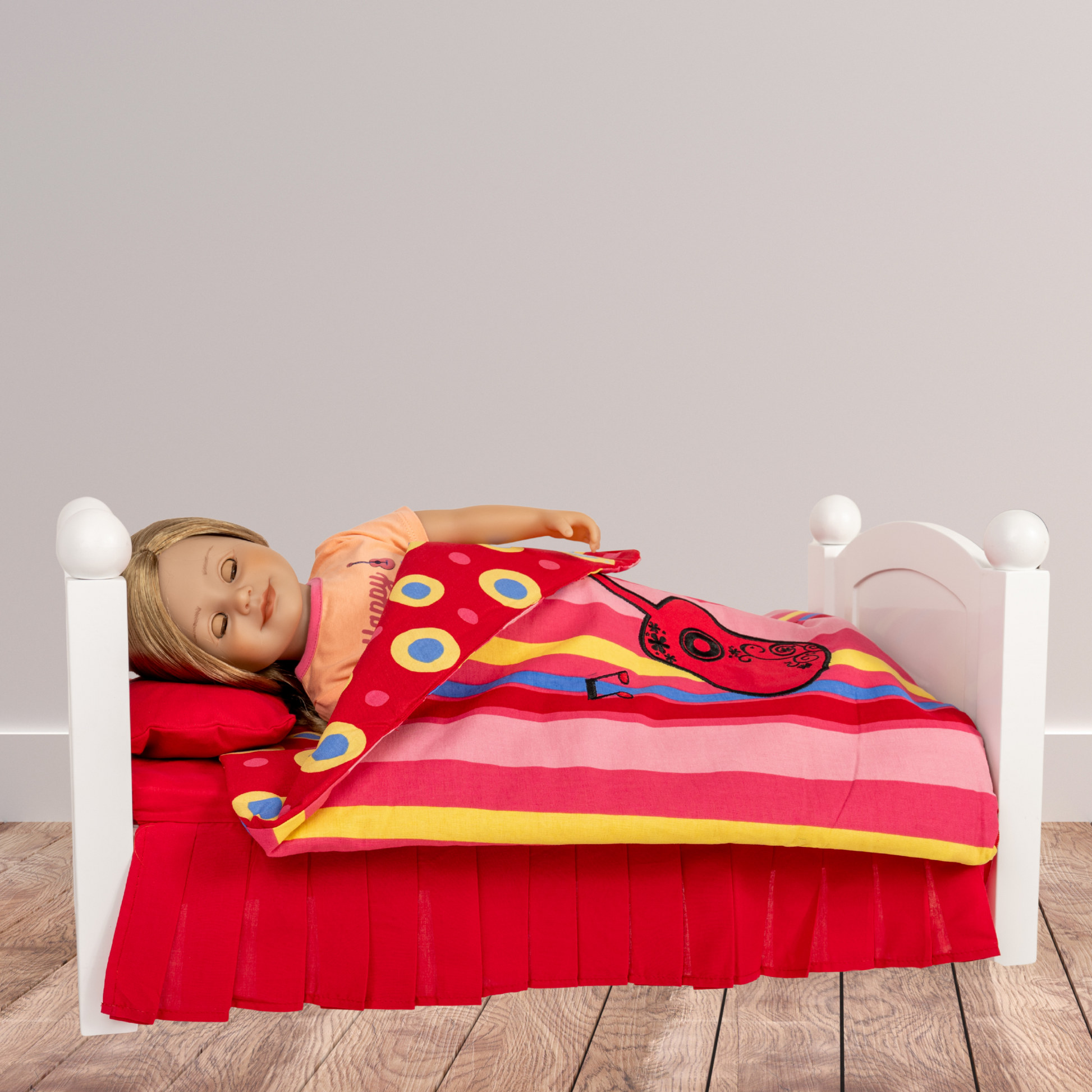 18-inch doll lying on a wooden bed with a red and yellow striped blanket featuring music notes and guitar.