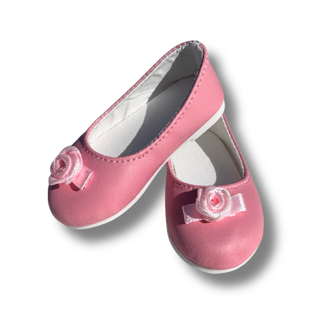 Pair of pink shoes with ribbon rosette flower details on the front.
