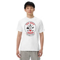 Adult model wearing a white “True North Canada” graphic T-shirt and light gray pants, standing against a light gray background. The shirt features a circular red-and-black design with crossed hockey sticks, a maple leaf, evergreen trees, a moose, and an Inukshuk, along with the words “True North,” “Canada,” and “Strong & Free.” The model faces forward with a neutral expression, showcasing the front of the shirt.