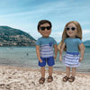 18-inch boy doll and girl doll wearing summer outfits and sunglasses on a beach in British Columbia