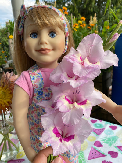Blue eye doll wearing floral overalls and pink tshirt.  Adorable outfit for 18 inch dolls.