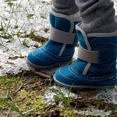 Winter snow boots on the feet of an 18-inch-doll walking on ice crystals