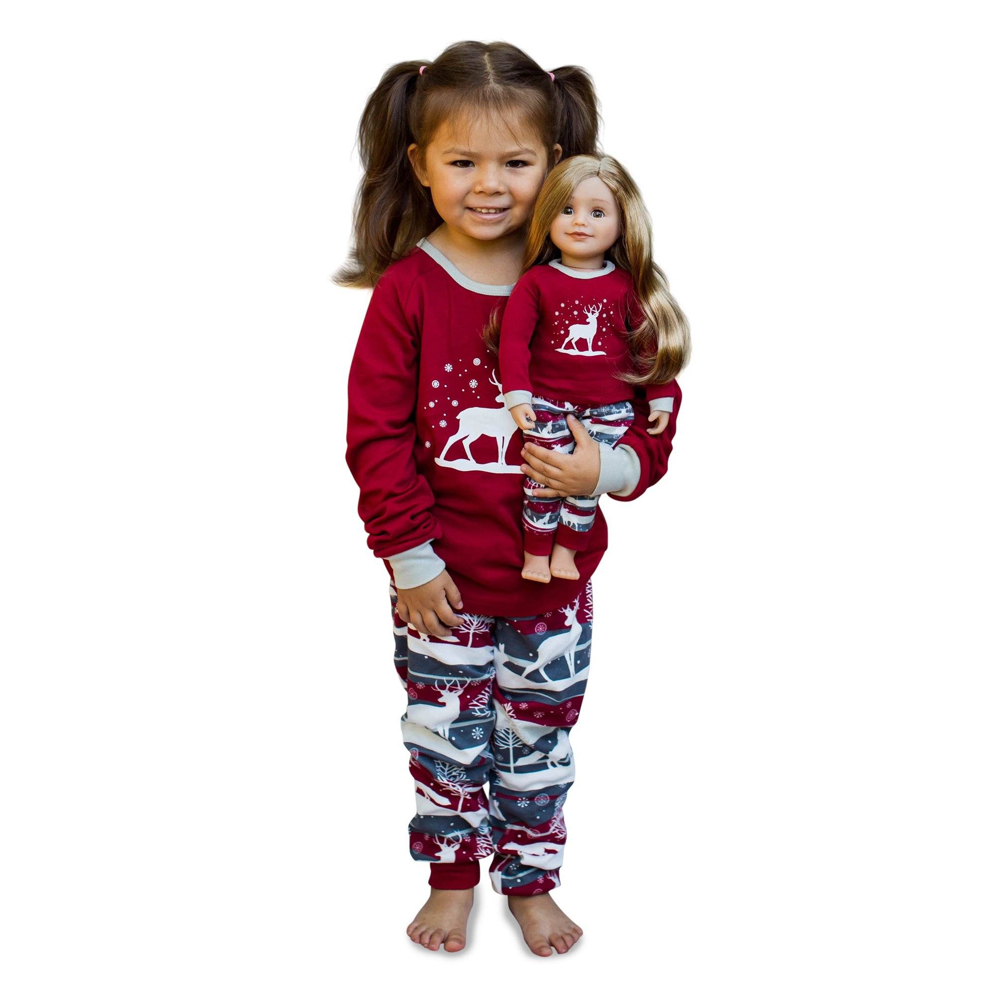 Little girl and doll dressing alike in matching pjs with winter theme.