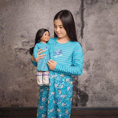 Girl with doll wearing matching dresses with an arctic animals design.