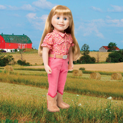 Maplelea 18 inch doll Brianne with story journal wearing pink patterned button-up shirt, pink pants, beige belt with sparkly buckle and beige riding boots. Shown in a Manitoba farm field.