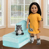 Toronto doll Alexi wears a nightshirt with raccoon graphic with a raccoon toy on her chair and wearing raccoon socks.