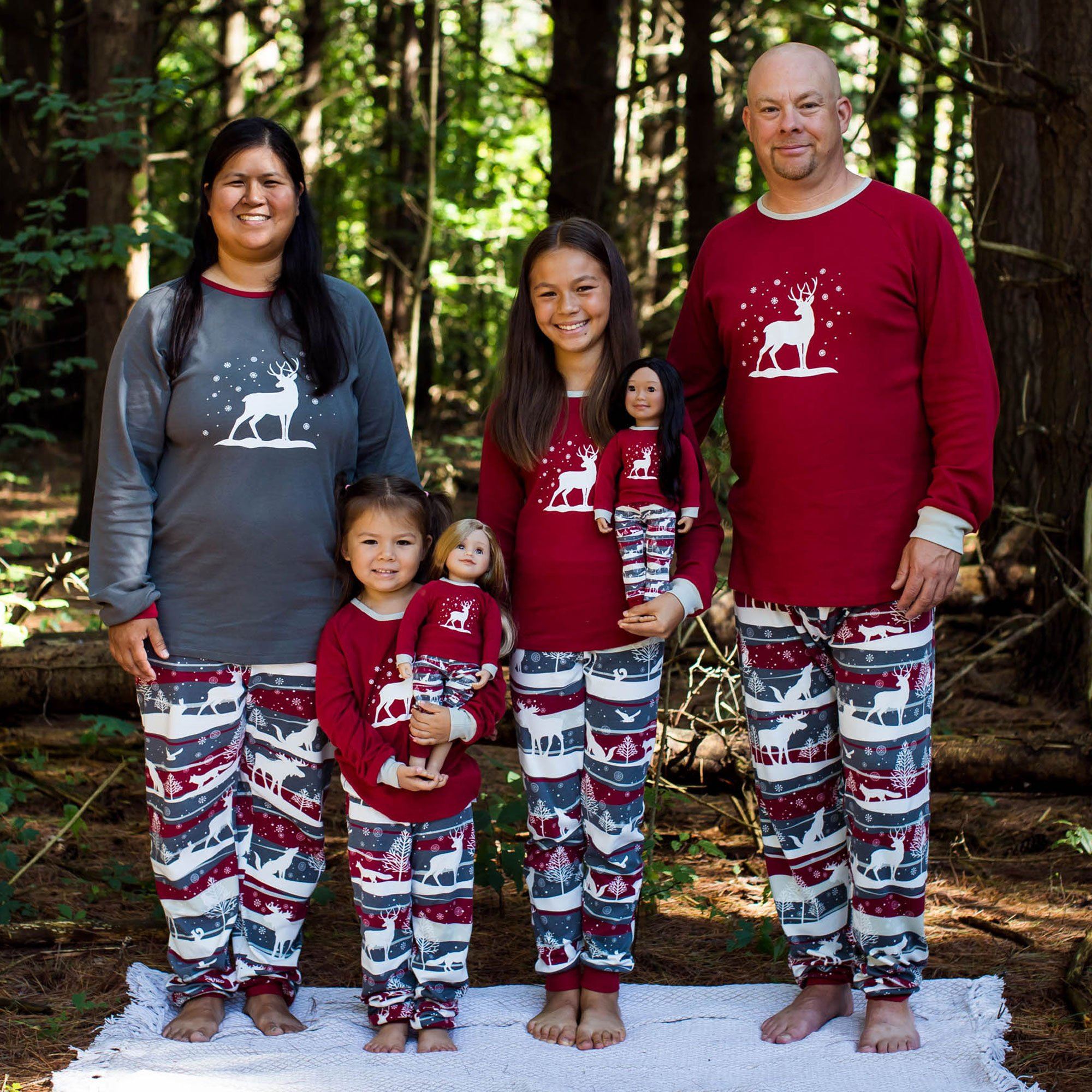 Mom dad two children and 18 inch dolls wearing matching pajamas with a winter theme.