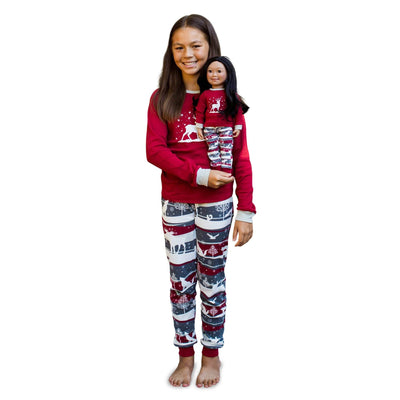 girl and her doll dressed in matching pajamas for Christmas.